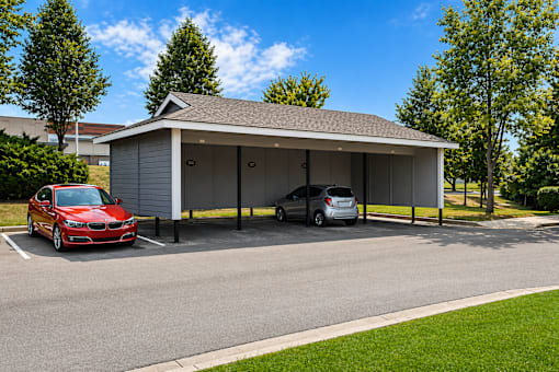 A red car is parked in front of a white garage.