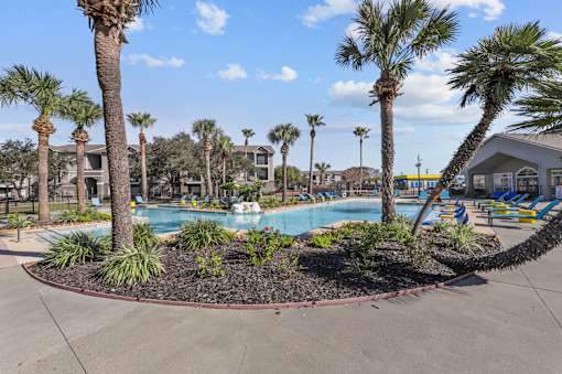 A pool surrounded by palm trees and plants.