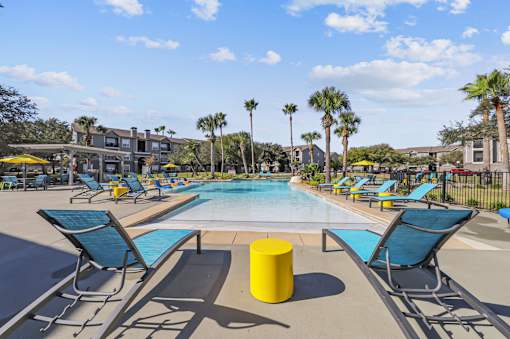 A pool area with sun loungers and palm trees.