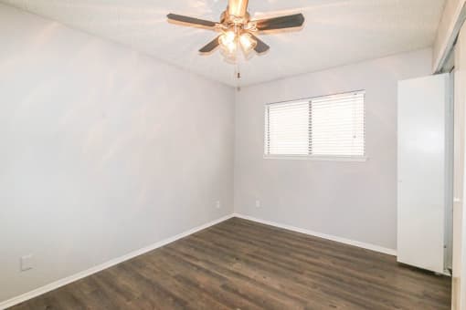 an empty bedroom with a ceiling fan and a window