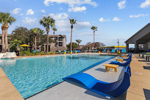 A pool with blue water and a yellow sun lounger.