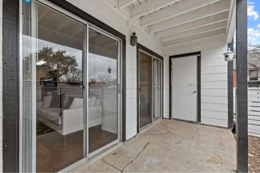 A patio with a sliding glass door and a white door.