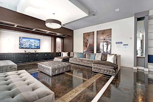 A modern living room with a grey sofa and a television on the wall.