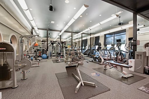 A gym with a variety of equipment including weights and cardio machines.