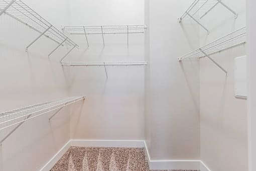 Empty white walk in closet with shelves.
