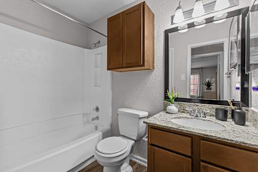 A white toilet sits next to a white bathtub in a bathroom.
