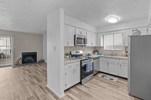 A kitchen with white cabinets and a wooden floor.
