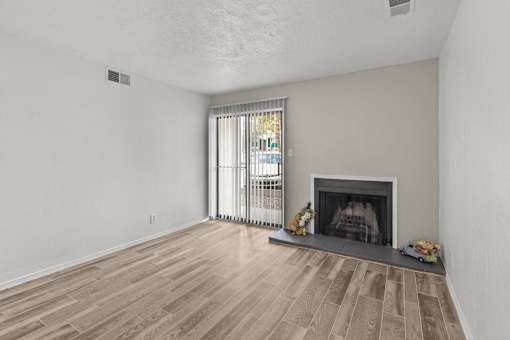 A living room with a fireplace and a window with curtains.