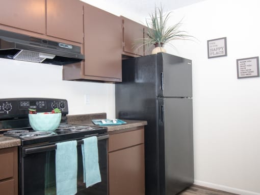 a kitchen with black appliances and brown cabinets and a black refrigerator