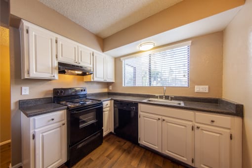 a kitchen with white cabinets and black appliances and a window