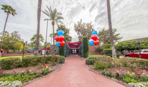 a walkway with colorful balloons at the entrance to a parking lot