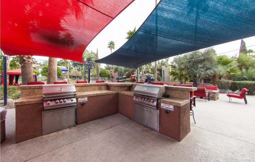 a patio with barbecue grills and umbrellas