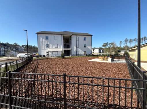 A white two-story building with a black fence in front.