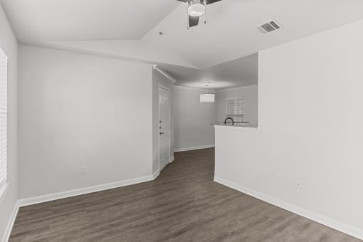 an empty living room and kitchen with white walls and wood flooring