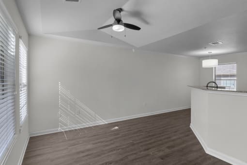 an empty living room with white walls and a ceiling fan