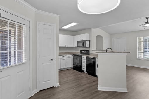 an empty kitchen with white cabinets and a black stove and
