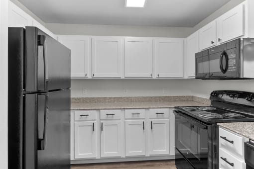 a kitchen with white cabinets and black appliances and a refrigerator