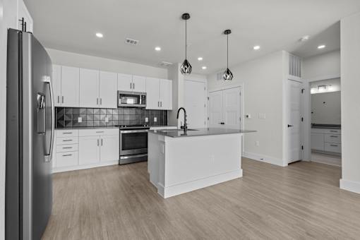 A modern kitchen with white cabinets and a wooden floor.