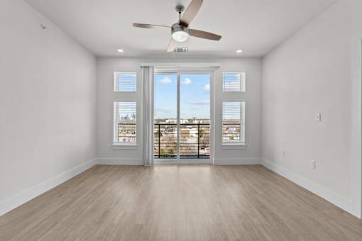 A room with a ceiling fan and sliding glass doors.