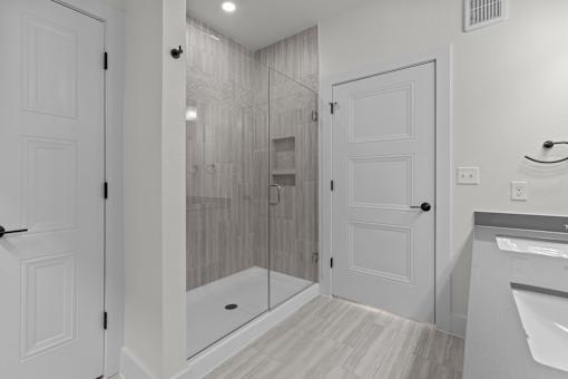 A bathroom with a walk-in shower and a white door.