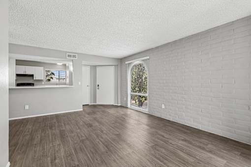 A room with wooden flooring and a white brick wall.