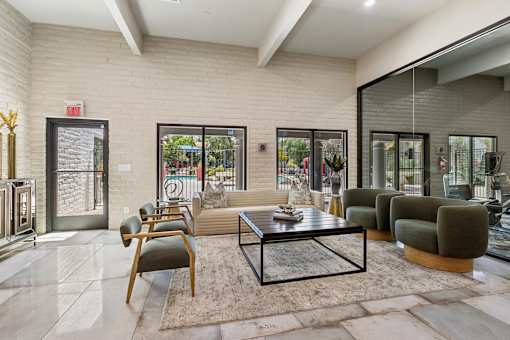 A modern living room with a glass coffee table and a view of the backyard.