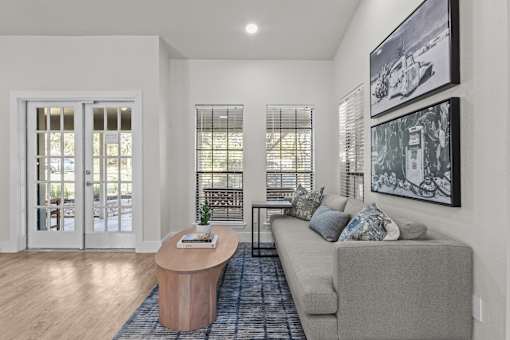 A living room with a grey couch, a wooden table, and a painting on the wall.