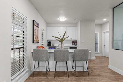 A kitchen with a bar area and two grey chairs.