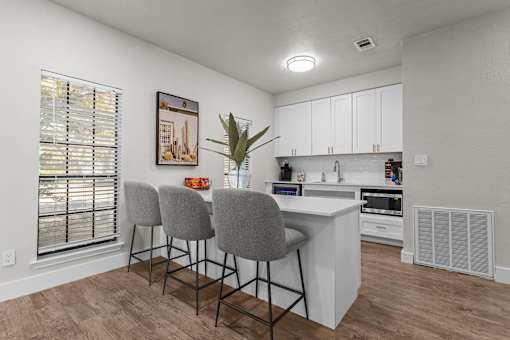 A kitchen with white cabinets and a wooden floor.