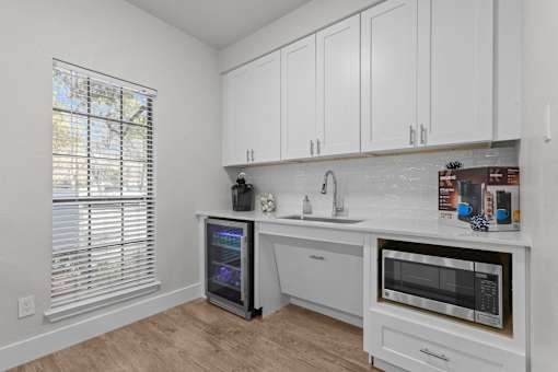 A kitchen with white cabinets and a black fridge.