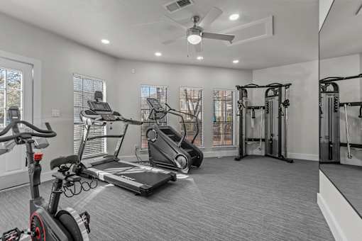 A spacious home gym with a treadmill, stationary bike, and weightlifting equipment.