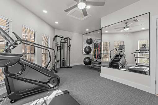 A well-equipped home gym with a treadmill, weights, and mirrors.