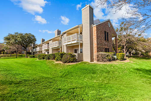 A large grassy area in front of a building with a balcony.
