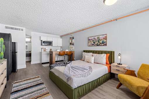 A bedroom with a bed, chair, and a cactus plant.