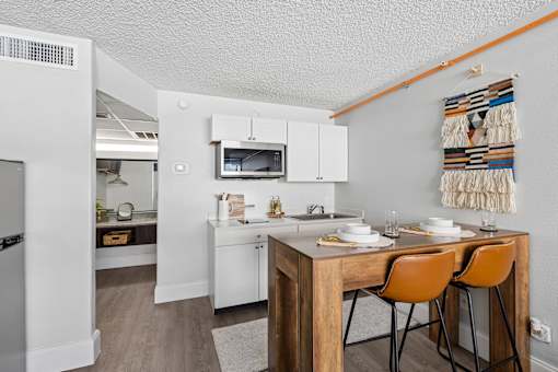 A kitchen with a wooden table and chairs and a white refrigerator.