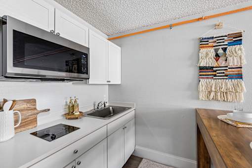 A kitchen with white cabinets and a microwave above the stove.