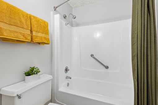 A white bathroom with a white tub and a white toilet.