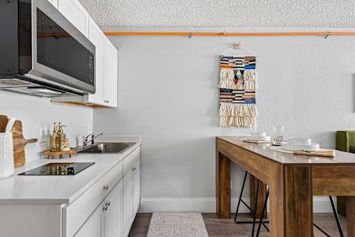 A kitchen with a white counter top and a wooden table.