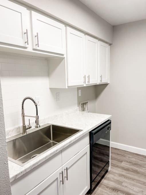 an empty kitchen with white cabinets and a sink