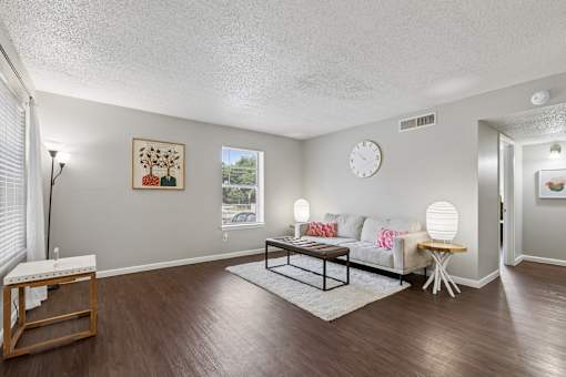 A living room with a white couch, a wooden coffee table, and a painting on the wall.