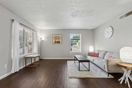 A living room with a grey couch, a coffee table, and a clock on the wall.