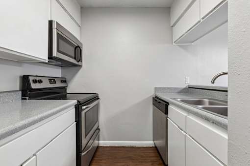 A kitchen with white cabinets and a black stove top oven.