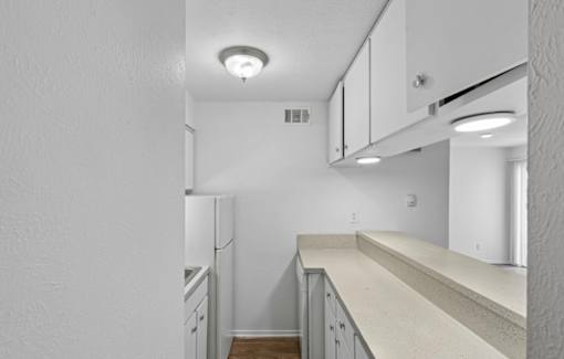 A kitchen with white cabinets and a white fridge.