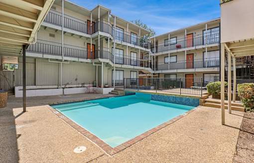 A swimming pool is surrounded by apartment buildings.