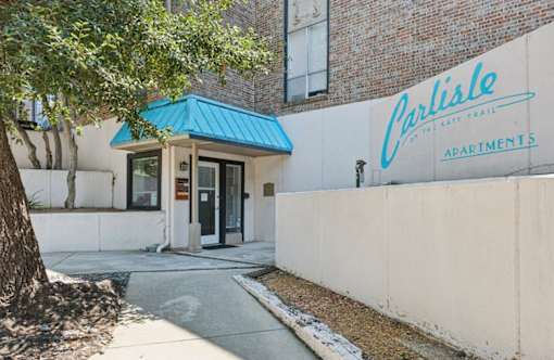 The entrance to Carlisle Apartments is shown with a blue awning.