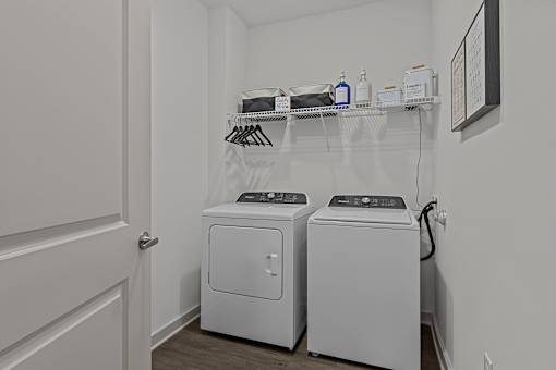 A laundry room with two washing machines and a shelf above them.