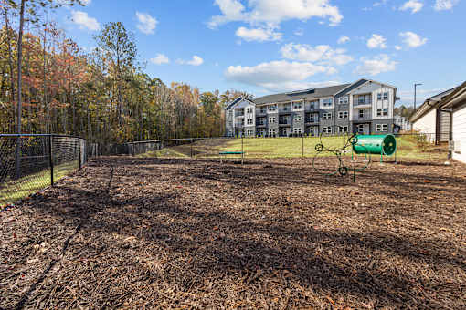 A playground with a green slide and a fence in the background.