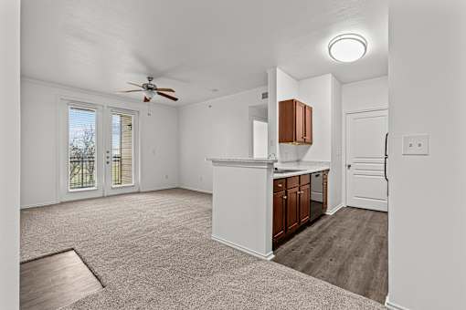 A spacious room with a ceiling fan and a kitchenette area.