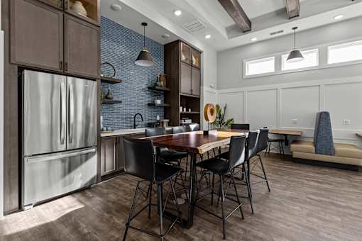 A kitchen with a table and chairs in the foreground and a refrigerator on the left.