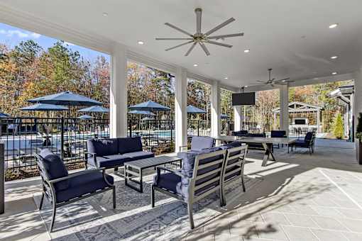 A patio with a table and chairs and a ceiling fan.
